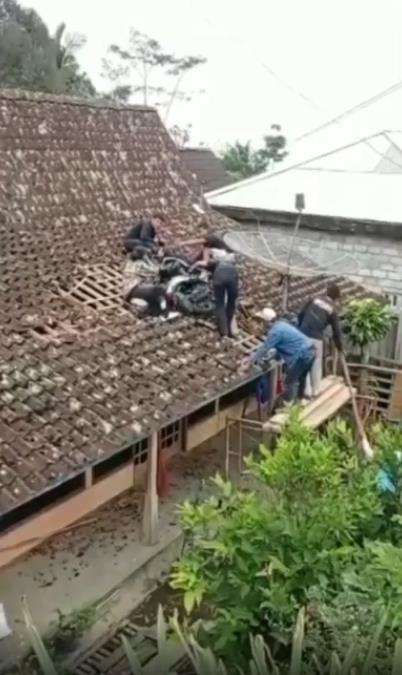 Motor matic nyangkut di atas genting rumah warga.