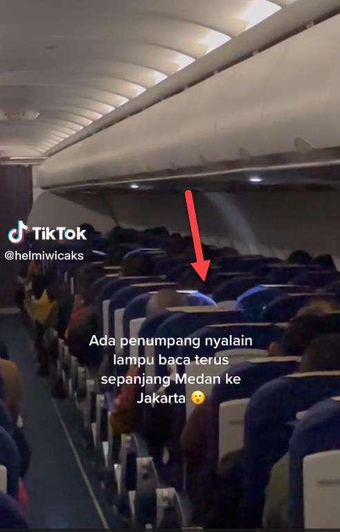 Penumpang nyalakan lampu baca selama penerbangan malam.