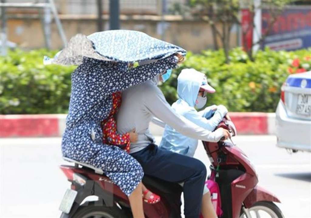 Pengemudi motor di Vietnam mencoba berlindung dari panas