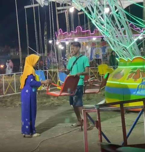 Nenek-nenek nekat bermain wahana ayunan putar di pasar malam.