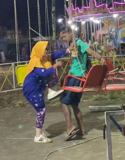 Nenek-nenek nekat bermain wahana ayunan putar di pasar malam.
