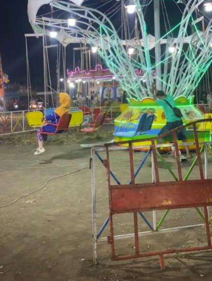 Nenek-nenek nekat bermain wahana ayunan putar di pasar malam.