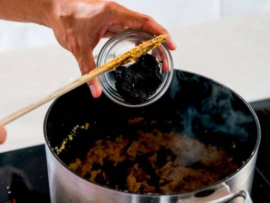 Seorang koki sedang memasak Rawon