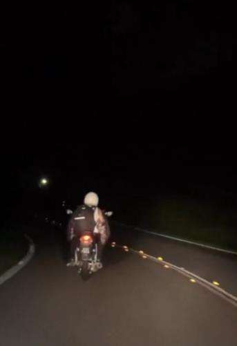 Aksi gadis kasih penerangan sepeda motor kakek tanpa lampu depan.