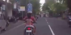 Ibu di Bali Naik Motor Bawa Galon Air Mineral di Kepala 